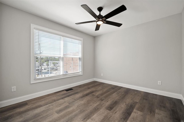 empty room featuring dark wood-type flooring, baseboards, and a ceiling fan