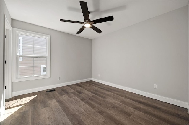 unfurnished room featuring dark wood-style flooring, a ceiling fan, and baseboards