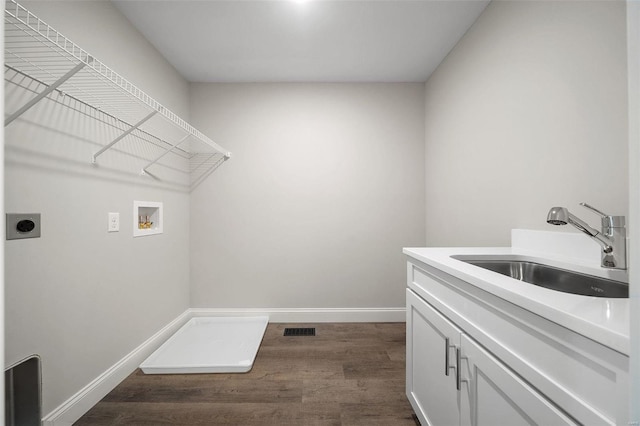 washroom featuring hookup for an electric dryer, washer hookup, dark wood-style flooring, baseboards, and cabinet space