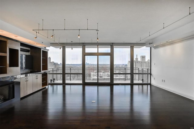 4909 Laclede Ave Unit 1401, Saint Louis, MO 63108 - unfurnished living room featuring dark wood finished floors, baseboards, rail lighting, and a wall of windows