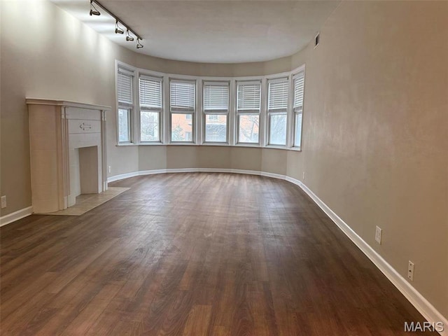 907 S Hanley Rd Unit 5, Clayton, MO 63105 - unfurnished living room with dark wood-style floors, rail lighting, and baseboards