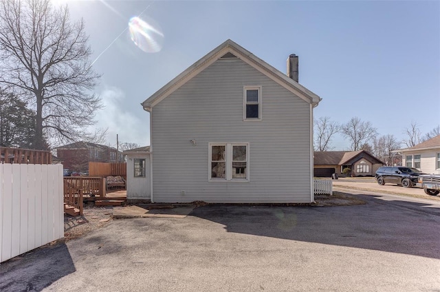 back of house with a chimney, a deck, and fence