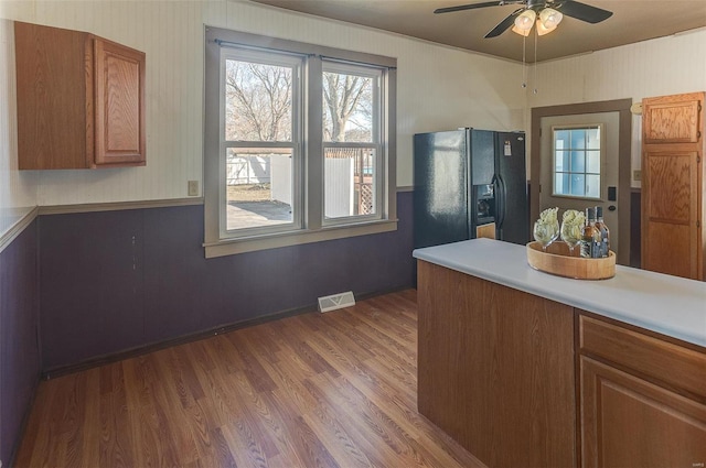 kitchen featuring black fridge, dark wood-style floors, light countertops, brown cabinets, and a ceiling fan