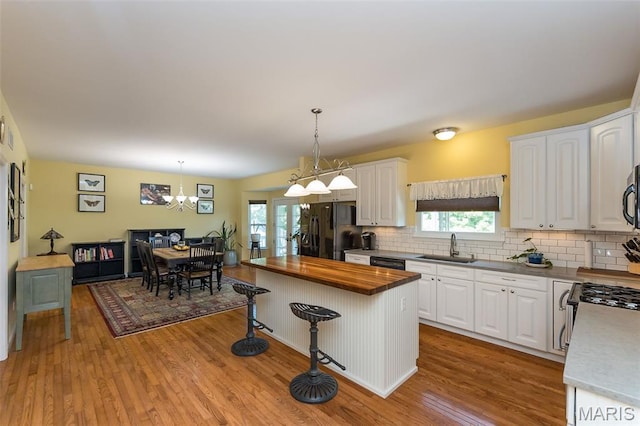 885 Morgan Rdg, High Ridge, MO 63049 - kitchen featuring black appliances, butcher block countertops, wood finished floors, a kitchen bar, and white cabinetry