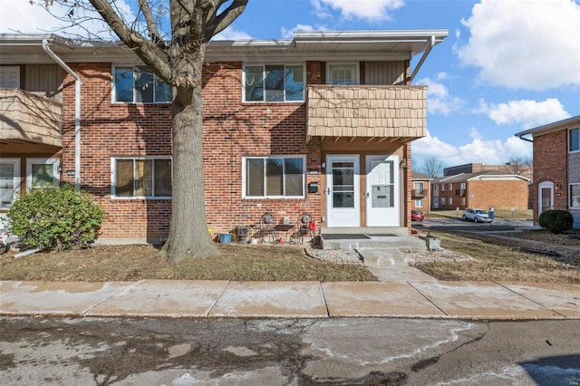 townhome / multi-family property featuring a balcony and brick siding