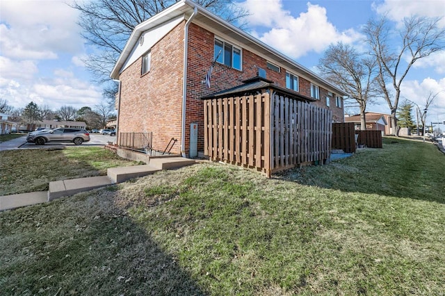 view of property exterior featuring brick siding and a yard