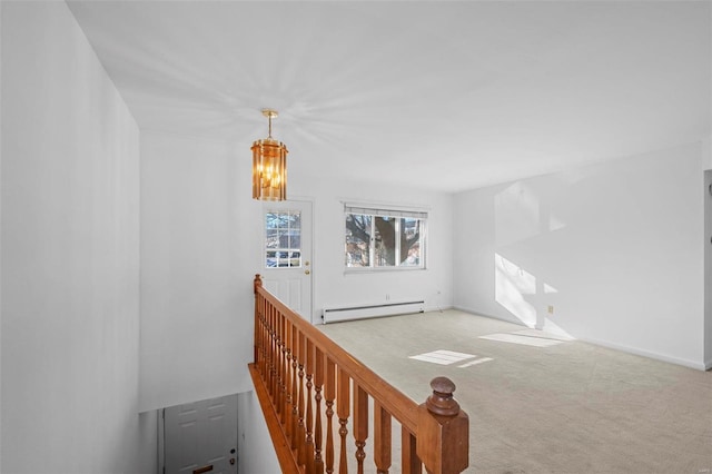 unfurnished room with a baseboard radiator, carpet floors, a chandelier, and baseboards