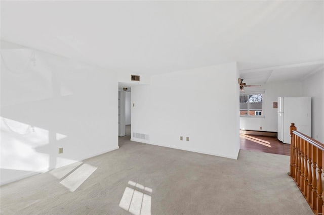 carpeted empty room with a baseboard radiator, baseboards, and a ceiling fan