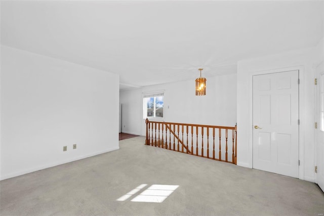 unfurnished room with carpet flooring, a chandelier, and baseboards