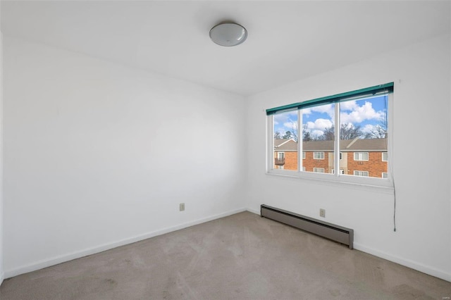 spare room featuring a baseboard heating unit, carpet, and baseboards