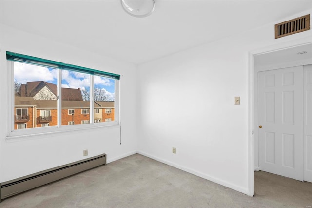carpeted spare room with a baseboard heating unit and baseboards