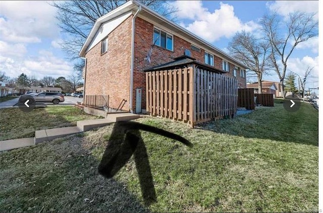 view of side of property with brick siding and a yard