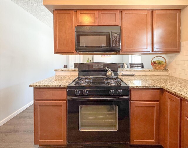 3253 Leisurewood Ct Unit G, Florissant, MO 63033 - kitchen featuring black appliances, wood finished floors, light stone counters, baseboards, and backsplash