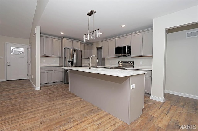 40 Butterfield, Farmington, MO 63640 - kitchen featuring appliances with stainless steel finishes, gray cabinets, light countertops, wood finished floors, and a kitchen island with sink