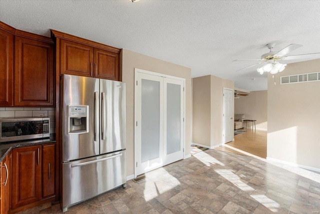 2537 Castle Pines Dr, Imperial, MO 63052 - kitchen with appliances with stainless steel finishes, stone finish flooring, ceiling fan, baseboards, and a textured ceiling