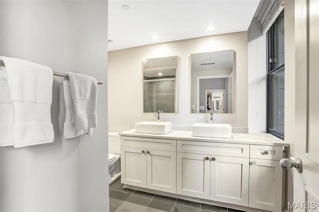 314 N Broadway Unit 903, Saint Louis, MO 63102 - bathroom featuring toilet, double vanity, a shower with door, tile patterned flooring, and recessed lighting