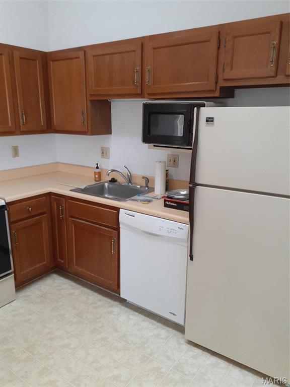 161 Eagle Rdg Unit 163-306, Ofallon, IL 62269 - kitchen featuring white appliances, a sink, light countertops, brown cabinetry, and light flooring