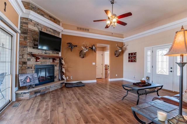450 Worth St, Holts Summit, MO 65043 - living room with crown molding, a ceiling fan, a stone fireplace, baseboards, and wood finished floors