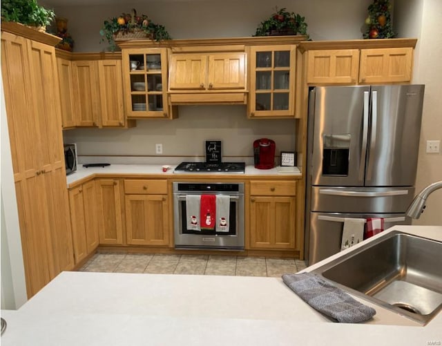 902 S Sutton Pl, Kennett, MO 63857 - kitchen featuring stainless steel appliances, light countertops, a sink, light tile patterned floors, and glass insert cabinets