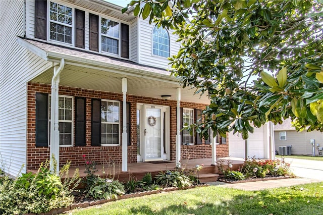 view of front of house with covered porch, brick siding, driveway, and central AC