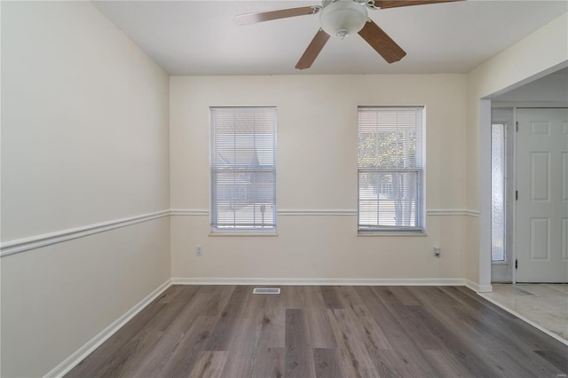 empty room with wood finished floors, ceiling fan, and baseboards