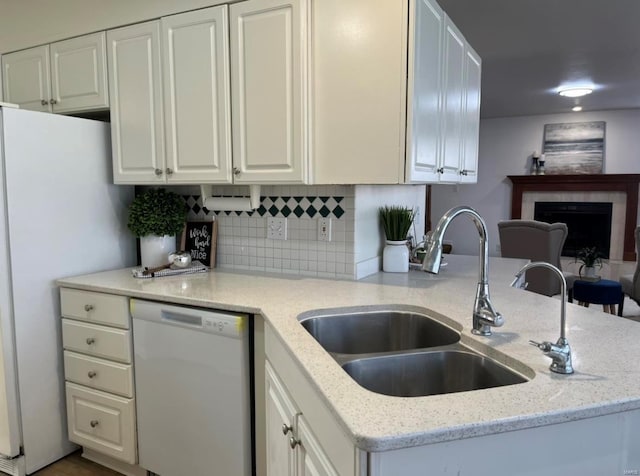 kitchen featuring white appliances, a sink, white cabinetry, light stone counters, and decorative backsplash