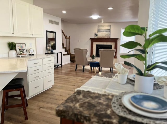 living room featuring stairs, wood finished floors, a fireplace, recessed lighting, and baseboards