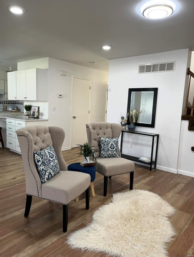 sitting room with wood finished floors, baseboards, recessed lighting, and stairs