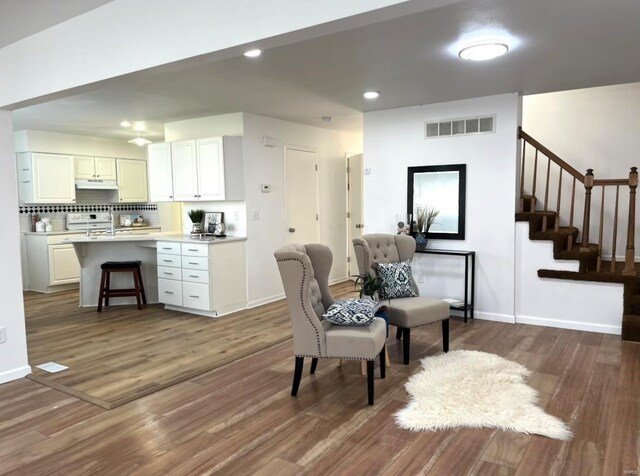 sitting room with dark wood-style floors, stairs, baseboards, and recessed lighting
