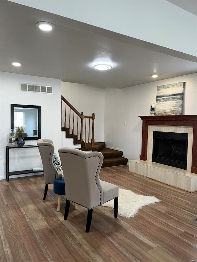living area featuring wood finished floors, stairs, a tiled fireplace, and recessed lighting