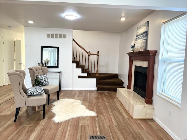 living area featuring stairway, wood finished floors, baseboards, and a tiled fireplace