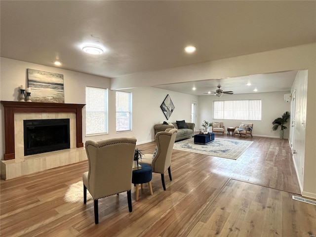 living room featuring wood finished floors, recessed lighting, baseboards, a ceiling fan, and a tiled fireplace