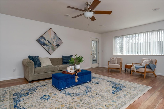 living area featuring a ceiling fan, wood finished floors, and baseboards
