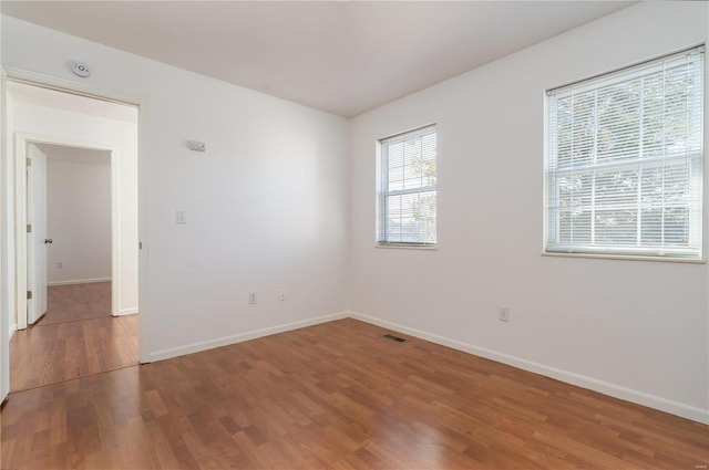 empty room with wood finished floors, baseboards, and a smoke detector