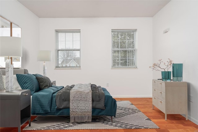bedroom with light wood-style floors, multiple windows, and baseboards