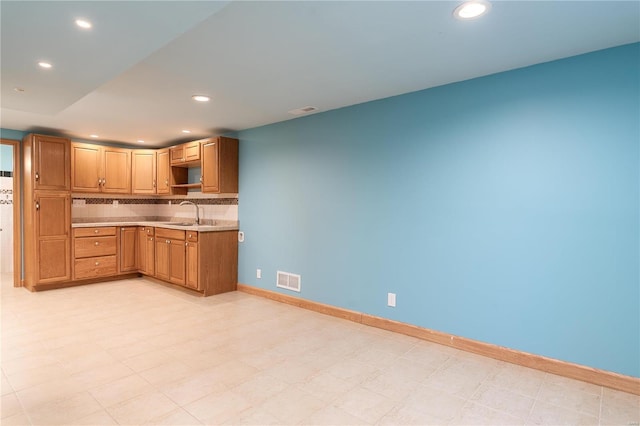 kitchen featuring light countertops, tasteful backsplash, baseboards, recessed lighting, and light flooring