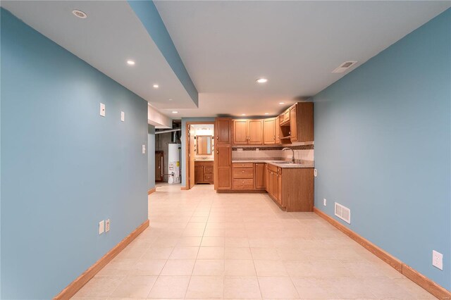 kitchen with water heater, recessed lighting, light countertops, backsplash, and a sink
