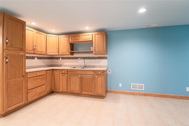 kitchen featuring a sink, light countertops, decorative backsplash, baseboards, and recessed lighting