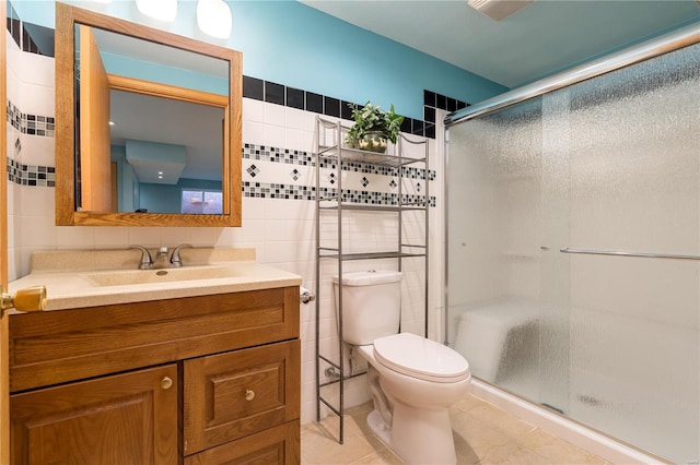full bath with tile walls, toilet, a stall shower, vanity, and tile patterned floors