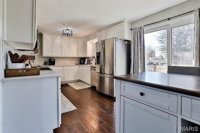 kitchen featuring appliances with stainless steel finishes, dark wood finished floors, a sink, white cabinets, and light countertops