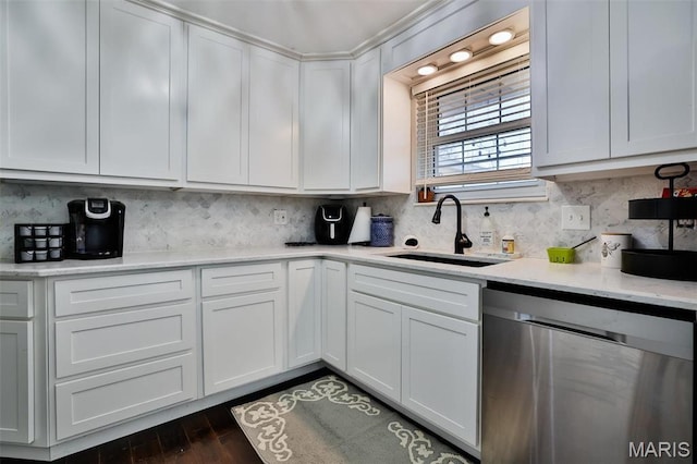 kitchen featuring stainless steel dishwasher, a sink, white cabinets, and backsplash
