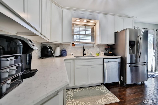 kitchen with appliances with stainless steel finishes, a sink, white cabinets, and backsplash