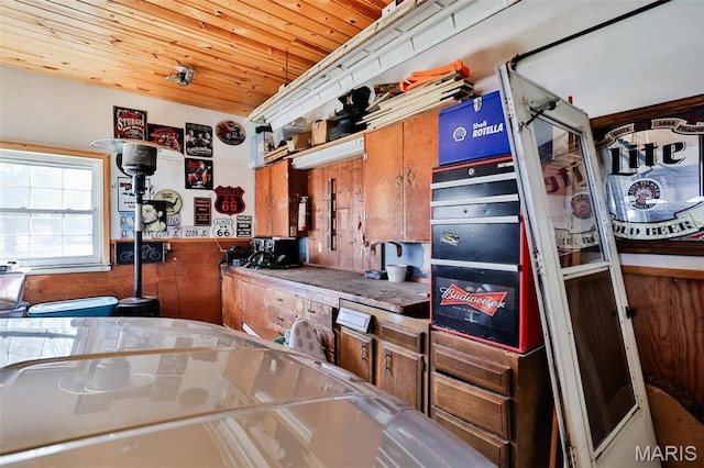 kitchen featuring stainless steel counters, wood ceiling, and wainscoting