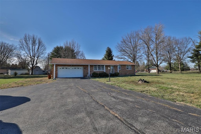 single story home featuring an attached garage, driveway, a front lawn, and brick siding