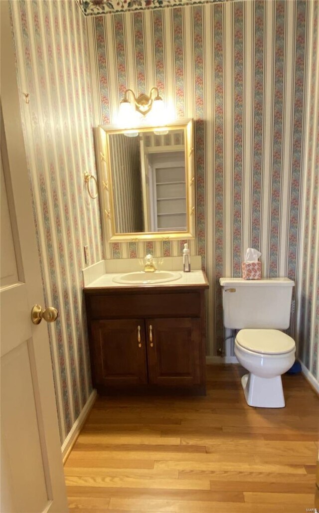 821 Oak Knoll Rd, Rolla, MO 65401 - bathroom featuring toilet, vanity, wood finished floors, wallpapered walls, and baseboards
