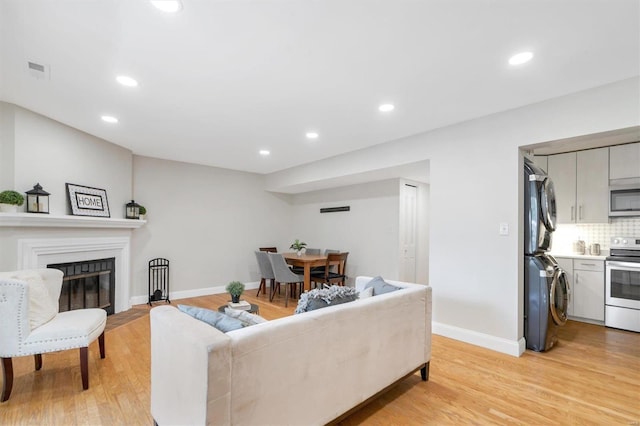 1418 Bluebird Ter, Saint Louis, MO 63144 - living room with estacked washer and dryer, light wood-style flooring, recessed lighting, a fireplace with flush hearth, and baseboards