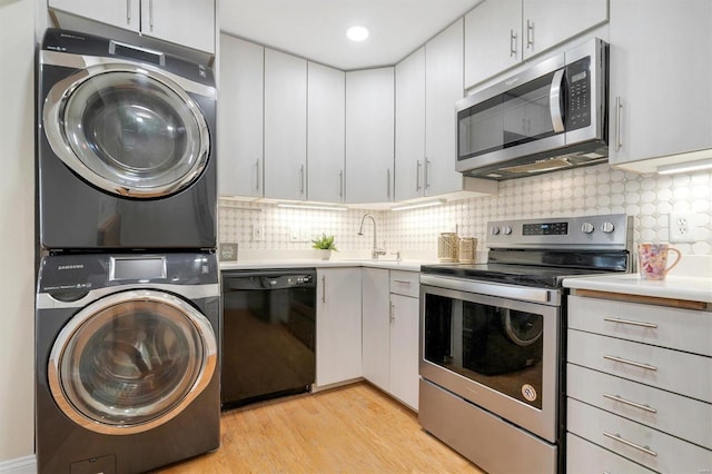 1418 Bluebird Ter, Saint Louis, MO 63144 - kitchen with appliances with stainless steel finishes, stacked washing machine and dryer, a sink, light countertops, and light wood-type flooring