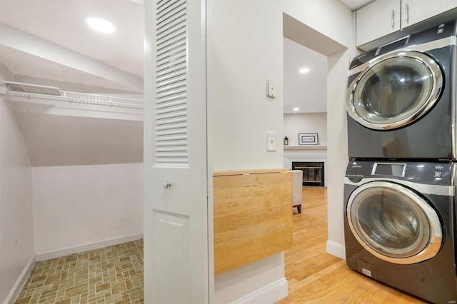 1418 Bluebird Ter, Saint Louis, MO 63144 - clothes washing area featuring stacked washing machine and dryer, baseboards, and a glass covered fireplace