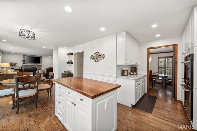 1578 Mason Knoll Rd, Town And Country, MO 63131 - kitchen with wood counters, a stone fireplace, recessed lighting, dark wood-type flooring, and white cabinetry