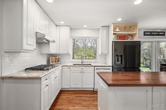 1578 Mason Knoll Rd, Town And Country, MO 63131 - kitchen with black refrigerator with ice dispenser, a sink, under cabinet range hood, stainless steel gas stovetop, and butcher block countertops